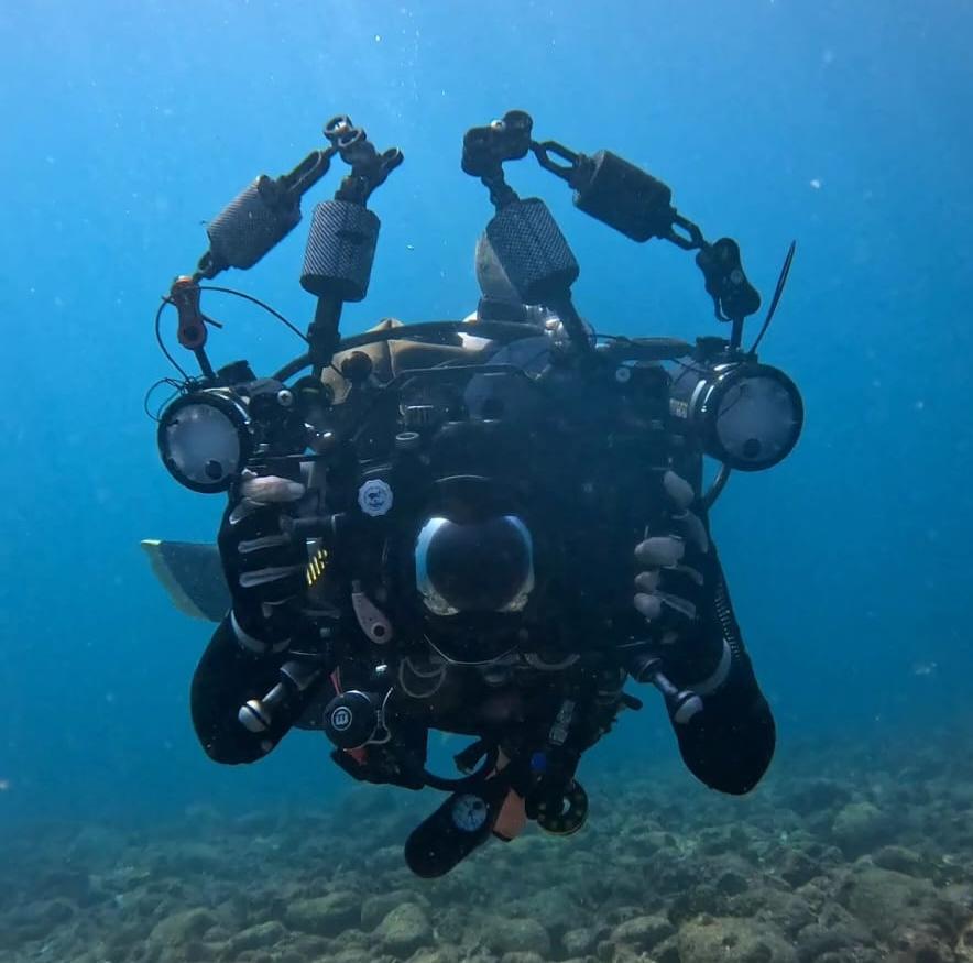 Mergulhador profissional com câmera e equipamento de filmagem subaquática